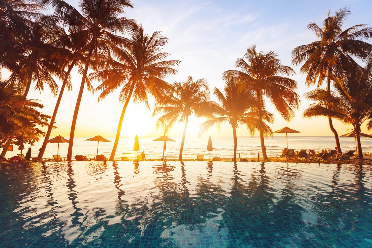 Tropical sunset with pool and palm trees
